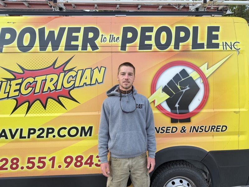 Person in a gray hoodie next to the yellow Power to the People van.