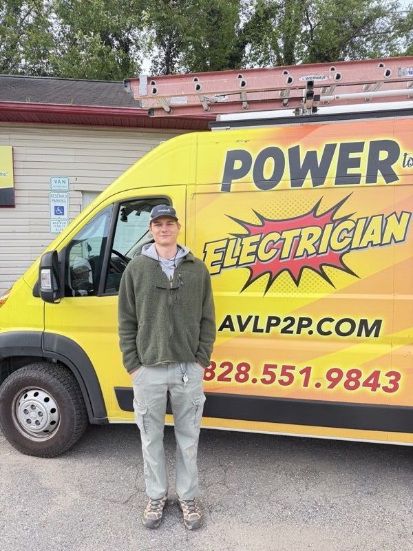 Person in an olive jacket with sunglasses on a ball cap, by the company van.