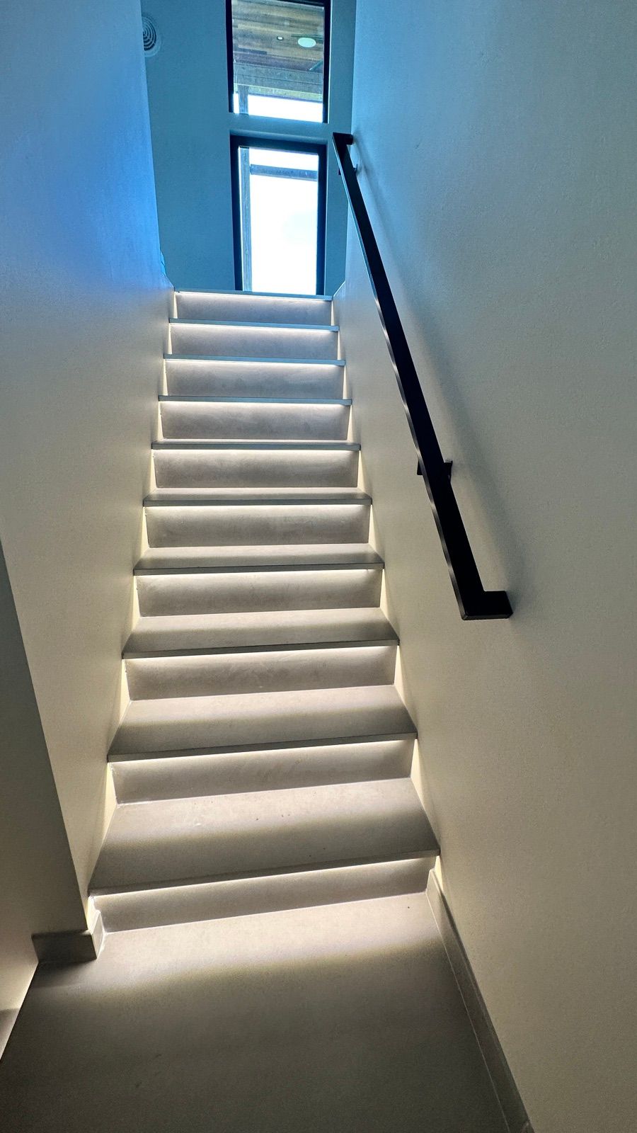 Asheville staircase with warm LED step lighting under each tread, leading up toward a tall window.