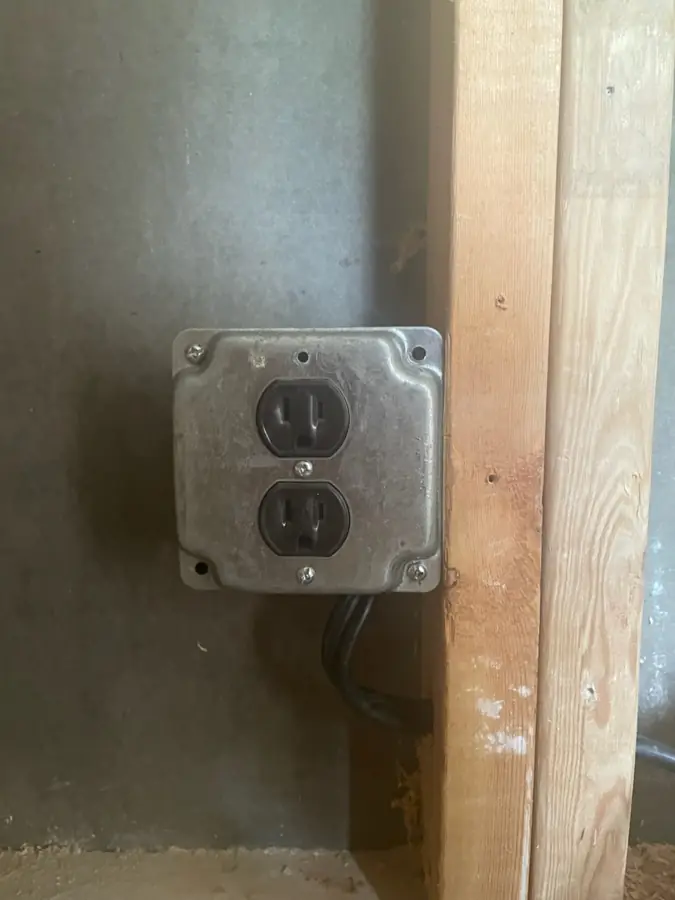 Duplex outlet installation in Asheville: a clean surface-mount metal box wired and ready in a local workspace