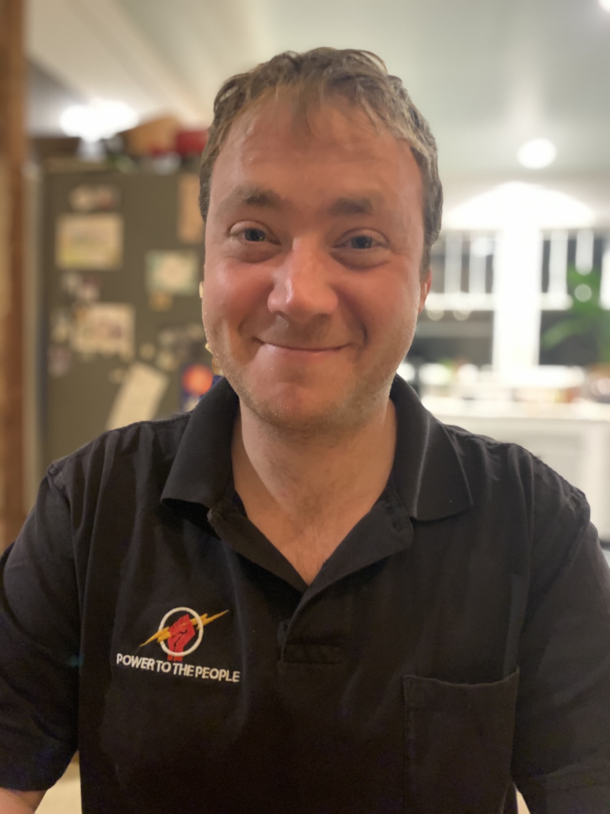 Andrew Holbein, owner of Power to the People, in the company polo with the fist-and-lightning logo