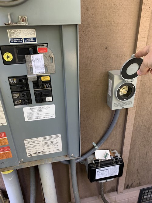 Square D electrical panel with a generator interlock kit and exterior power-inlet box installed on the side of an Asheville home