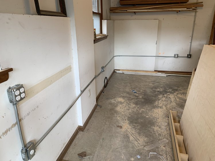 Mid-rewire rough-in inside an Asheville home — fresh metal conduit run with new outlet boxes mounted along the walls