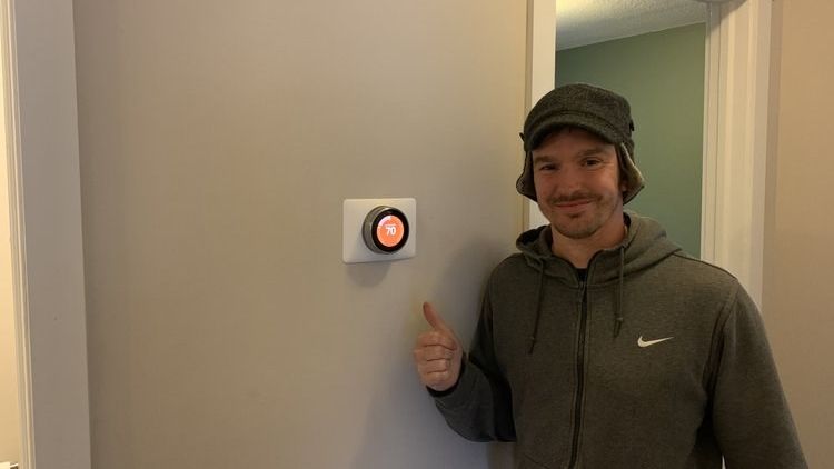 A Power to the People electrician giving a thumbs-up beside a newly installed and powered-up wall control in a finished Asheville home